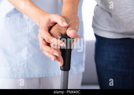 Custode femmina assistere felice Senior uomo mentre passeggiate a casa Foto Stock