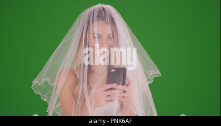 Sposa abiti da sposa e il velo di prendere una selfie con lo smartphone su schermo verde Foto Stock