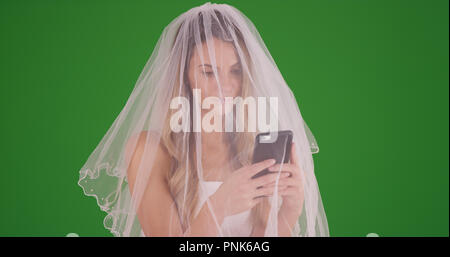Giovane sposa caucasica texting sul suo smartphone su schermo verde Foto Stock