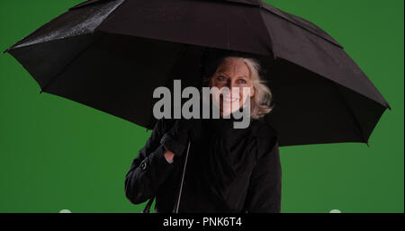 Felice bianco donna anziana holding ombrello in caso di pioggia su schermo verde Foto Stock