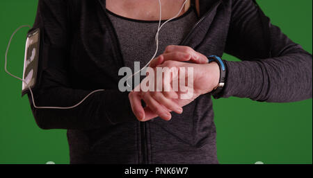 Primo piano della donna controllo pareggiatore guardare in sportswear su schermo verde Foto Stock