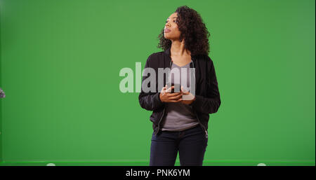 Donna Moderna usando il telefono per ottenere indicazioni dopo perdersi su schermo verde Foto Stock