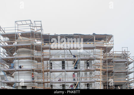 Costruzione professionale dei lavoratori sul patibolo ascensore parete isolata facciata con lana minerale. conciatetti indossare l'imbragatura di sicurezza la parete isolante fac Foto Stock