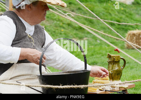 TONBRIDGE, Inghilterra - 8 Settembre 2018: Donna vestito in abiti medievali si siede in una pentola di cera fusa, fare candele a un open air heritage fest Foto Stock