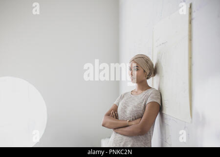 Insegnante musulmano appoggiata contro la lavagna in aula Foto Stock