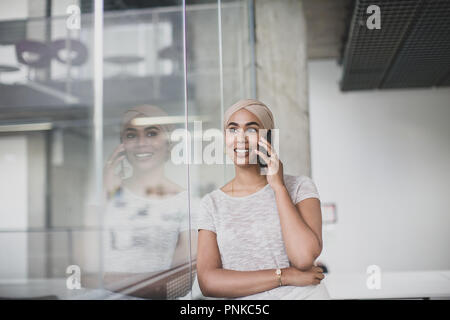 Imprenditrice musulmana utilizzando uno smartphone in un ufficio Foto Stock