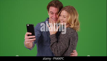 Felice fidanzati tenendo selfie con il cellulare su schermo verde Foto Stock