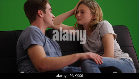 Caucasian giovane seduto sul divano una conversazione su schermo verde Foto Stock