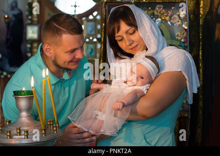 La Bielorussia, Gomel, il 14 luglio 2018. La chiesa è Zyabrsky. I genitori sono battezzati da un bambino. Madrine. Mamma e papà tenere il bambino in braccio nella Foto Stock