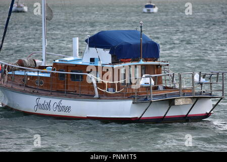 Motorsailor classico con ponti e cabina in color legno ormeggiata su grigio mare increspato. Foto Stock