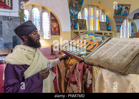 Lettura di Monaco da 500 anni di Nuovo Testamento la Bibbia libro di preghiera, interno alla nuova cattedrale di Tsion Maryan, Santa Maria di Sion, Axum, Etiopia. 3 wi Foto Stock