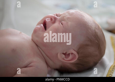 La Bielorussia, Gomel, il 14 luglio 2018. Chiesa Zyabrovskaya. Ortodossi il battesimo di un bambino. La faccia di un pianto neonato Foto Stock