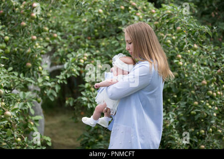 La Bielorussia, Gomel, il 14 luglio 2018. Una vacanza nel villaggio di Zyabrovka. Madre con bambino neonato in apple Orchard Foto Stock