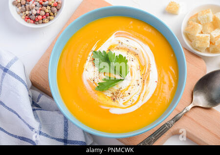 Zuppa di zucca con panna e prezzemolo sul tavolo bianco. Foto Stock