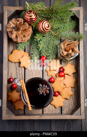 Natale vin brulé. Concetto di vacanza decorate con rami di abete, Gingerbread Cookies e mirtilli rossi sul legno scuro vassoio. Foto Stock