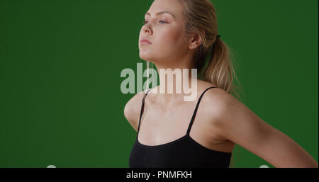 Bianco millenario ragazza in abbigliamento da palestra guardare fuori nella distanza su schermo verde Foto Stock
