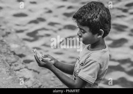 Il governo dello Sri Lanka povero bambino di strada contando il denaro a Tissamaharama Foto Stock