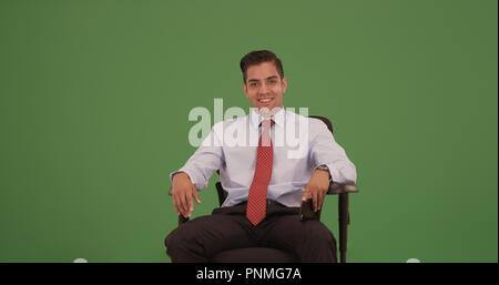 Corporate professional seduto nella sedia ufficio guardando la fotocamera su schermo verde Foto Stock