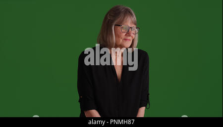 Premuto anziana donna bianca contemplando su schermo verde Foto Stock