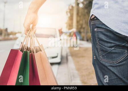 Stretta di mano di uomo con sacchetto di carta e dello shopping a piedi auto e amico di ragazza in attesa. Foto Stock