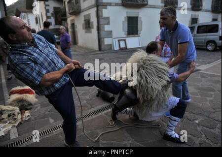 Ituren, Spagna. Il 22 settembre, 2018. Un uomo vede calciare Joaldunak vestito con pelli di pecora, cappuccio chiamato tunturro e campanacci durante il giorno di Joaldunak.Giorno del joaldunak in Ituren (Navarra), Spagna. Il Joaldunak vestito in pelli di pecora, cappuccio chiamato tunturro e campanacci, questi li rendono il suono per la città e gli ascensori, il risveglio della madre terra per fornire migliori frutti. Qualcuno vestito come un orso (hartza) chi è il responsabile per spaventare le persone e gli spiriti cattivi. Credito: Elsa un bravo/SOPA Immagini/ZUMA filo/Alamy Live News Foto Stock