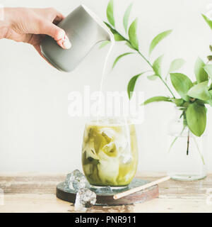 Iced matcha latte di cocco con il latte in bottiglie di vetro, quadrato ritaglia Foto Stock