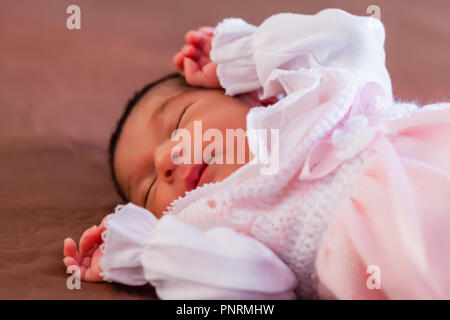 Carino a due settimane bambino neonato bambina indossa morbida maglia rosa vestiti, dormire serenamente nel letto Foto Stock