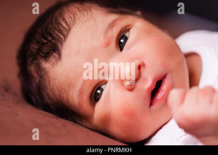 Close up ritratto di un simpatico due settimane bambino neonato bambina coricata, apre gli occhi e si guarda intorno Foto Stock