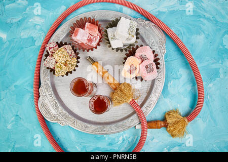 Set di varie delizie turche in argento tradizionale vaschetta sul vassoio di metallo vicino hookah tubo sfondo blu medio orientale dessert. Vista dall'alto. Foto Stock