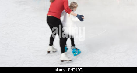 Belgrado, Serbia - Gennaio 8, 2018: Bambina imparare a pattinare tenendo le mani con l'istruttore madre, da dietro Foto Stock