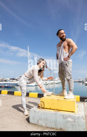 Giovane coppia sportiva avente una pausa tra la formazione e la preparazione per eseguire presso il molo. Foto Stock