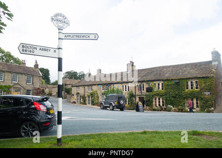 Il villaggio di Burnsall, un centro per la camminata in Wharfedale superiore, nello Yorkshire, Regno Unito, con il Red Lion Hotel in background Foto Stock