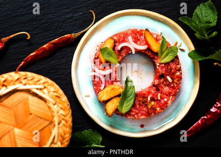 Concetto di cibo crudo speziato Larb Thai, Tartara di manzo stile tailandese sul nero ardesia scheda con spazio di copia Foto Stock