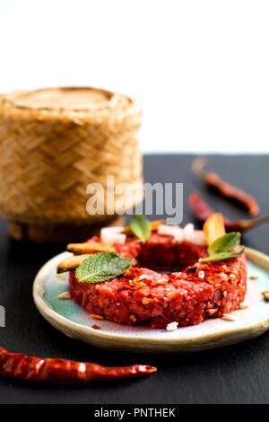 Concetto di cibo crudo speziato Larb Thai, Tartara di manzo stile tailandese sul nero ardesia scheda con spazio di copia Foto Stock