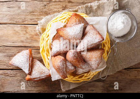 Mandazi, noto anche come il dabo o sud sudanese ciambella cocco close-up in un cesto su una tavola orizzontale di vista in pianta da sopra Foto Stock