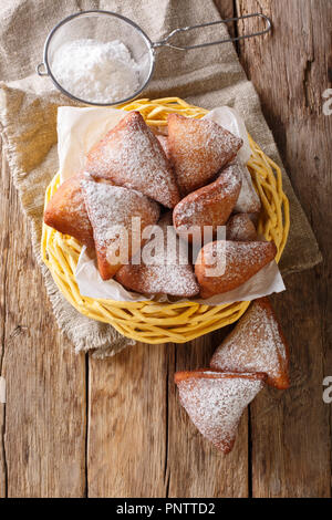 Mandazi, noto anche come il dabo o sud sudanese ciambella cocco close-up in un cesto su un tavolo. Verticale in alto vista da sopra Foto Stock