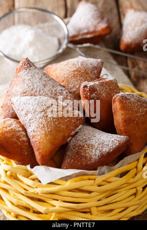 Mandazi, noto anche come il dabo o sud sudanese ciambella cocco close-up in un cesto su un tavolo. In verticale Foto Stock