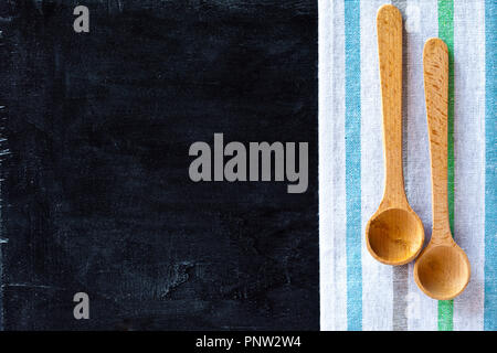 Cucchiai di legno e la tovaglia su sfondo blackboard Foto Stock