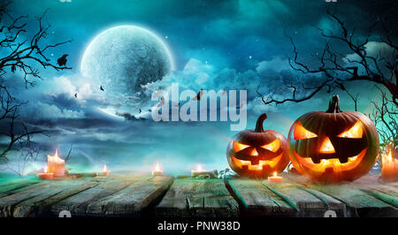 Halloween - Jack O' lanterne e candele sulla tavola nella notte nebbiosa Foto Stock