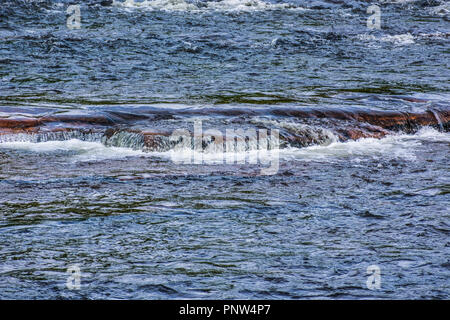 Un fiume scorre su rocce per formare piccole cascate Foto Stock