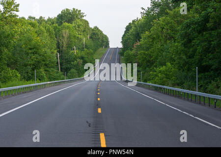 Un auto scompare oltre la collina come continua il suo viaggio verso la strada Foto Stock