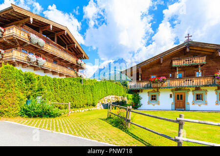 Tradizionale alpino in legno case decorate con fiori sul prato verde a Going am Wilden Kaiser villaggio montano su soleggiate giornate estive, Tirolo, Austria Foto Stock