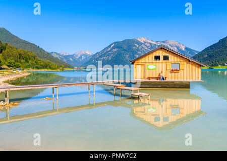 ACHENSEE LAKE, AUSTRIA - JUL 31, 2018: Wooden boat house and pier of shore of beautiful Achensee lake on sunny summer day. Lake Achensee, also called  Foto Stock