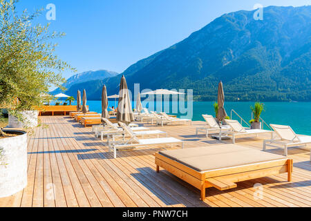 Sedie sul molo a Pertisau cittadina sulla soleggiata giornata estiva sulla riva del lago Achensee, Tirolo, Austria Foto Stock