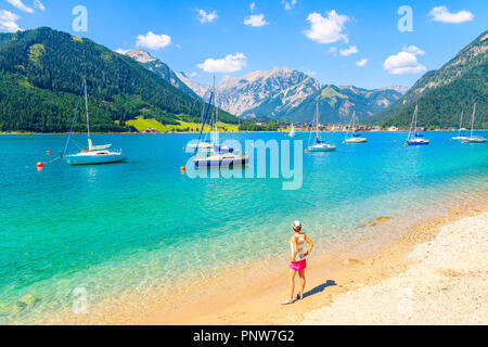 Giovane donna in piedi turistica sul bellissimo lago Achensee sulla spiaggia soleggiata giornata estiva, Tirolo, Austria Foto Stock