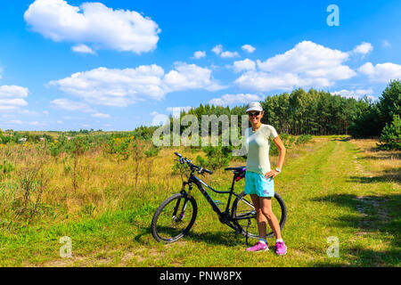 Pista ciclabile vicino OLKUSZ, Polonia - 9 Sep, 2018: giovane donna con la bicicletta e vista della foresta verde sulla soleggiata giornata estiva. Polonia meridionale ha molti attarente, Foto Stock