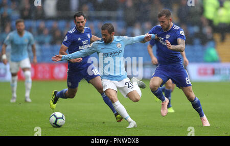 Manchester City's Bernardo Silva (centro) e Cardiff City è Joe Ralls battaglia per la palla durante il match di Premier League al Cardiff City Stadium. Foto Stock