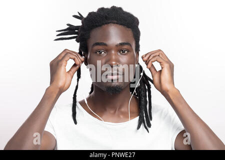 Dark scuoiati uomo con dreadlocks ascoltando musica le cuffie Foto Stock