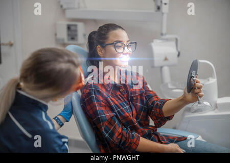 Chiusura del dentista donna e donna giovane azienda client specchio e sorridente. Foto Stock