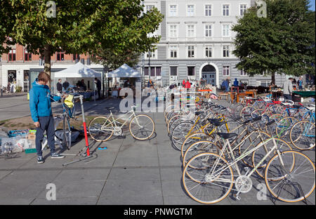 Giovani bicicletta meccanica di assemblaggio e vendita di biciclette a sabato il mercato delle pulci di Israels Plads, Israels Square, nella soleggiata autunnale di Copenaghen. Foto Stock